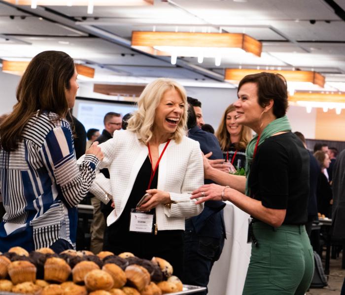 Three women talking and laughing at an event 