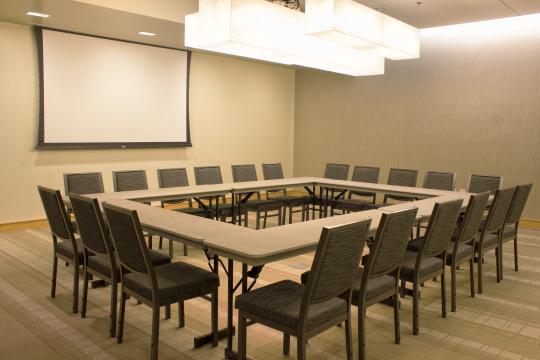 a room with a square table and a projection screen