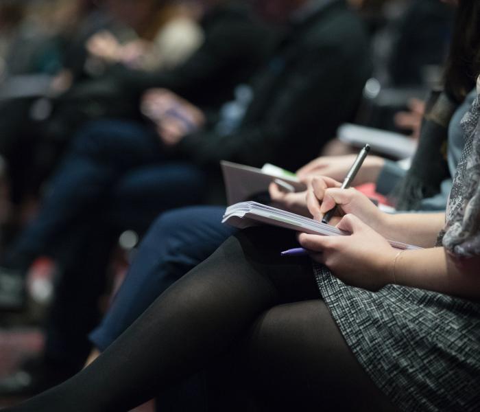 People taking notes at a conference