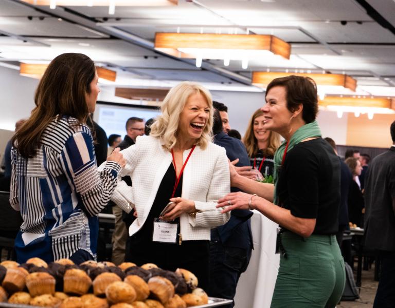 Three women talking and laughing at an event 
