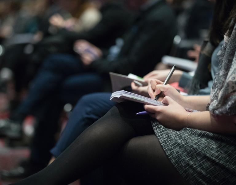 People taking notes at a conference
