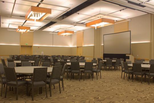 an interior space with round tables, chairs, and a stage