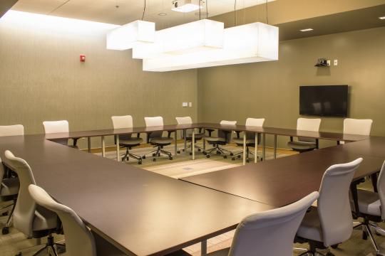 a room with light green walls, dark tables, and a screen