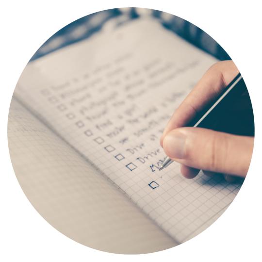 a paper with a list on it and a hand holding a pen ready to write
