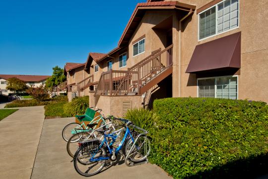 light brown two story buildings with tile roof and window awnings 