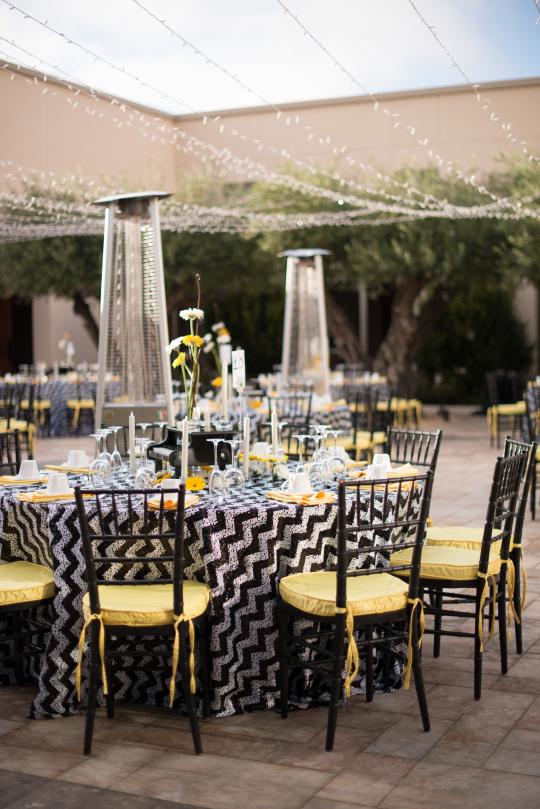 Event table setup with glassware and string lights above tables 
