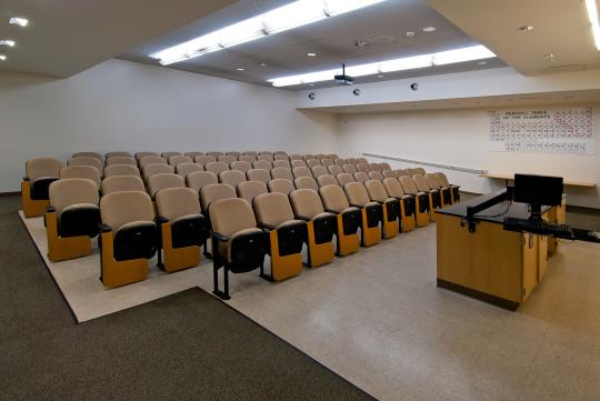 interior of classroom space with sloped ceilings and skylights with rows of beige chairs