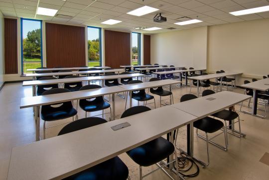 spacious interior of classroom with three floor to ceiling window panels overlooking a green lawn