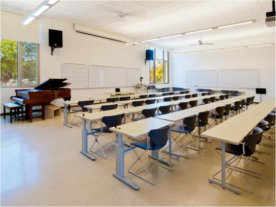 classroom interior with white walls and large windows and a piano