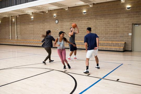 four students playing basketball