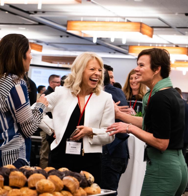 Three women talking and laughing at an event 