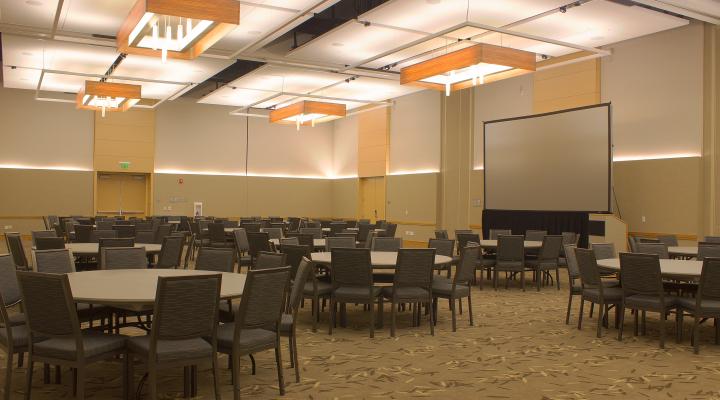 an interior space with round tables, chairs, and a stage