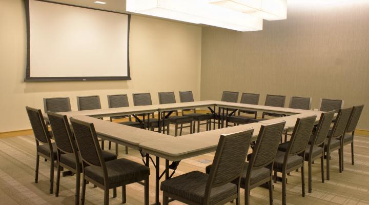 a room with a square table and a projection screen