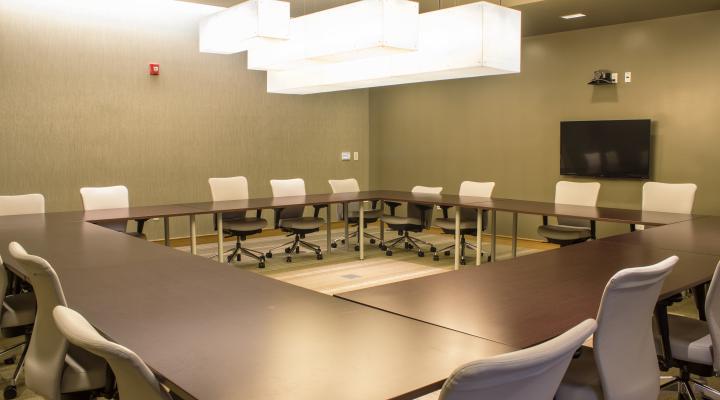 a room with light green walls, dark tables, and a screen